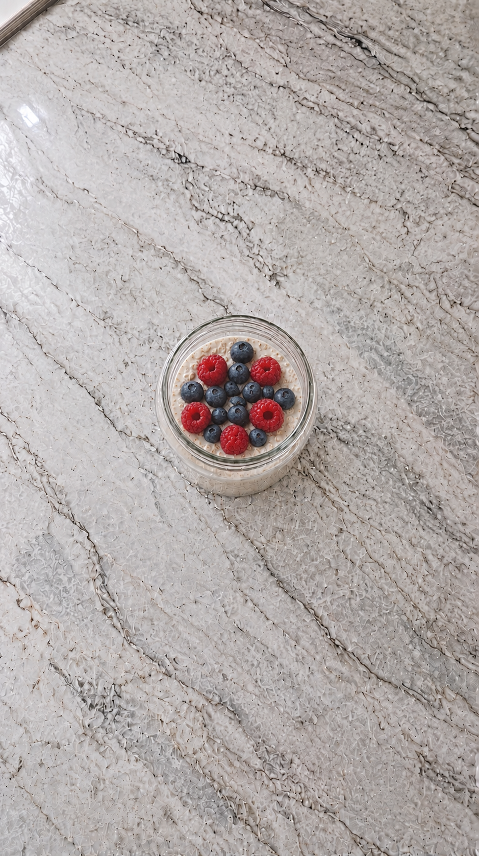 High Protein Overnight Oats For Weight Loss high protein overnight oats in a glass jar topped with raspberries and blueberries on marble countertop
