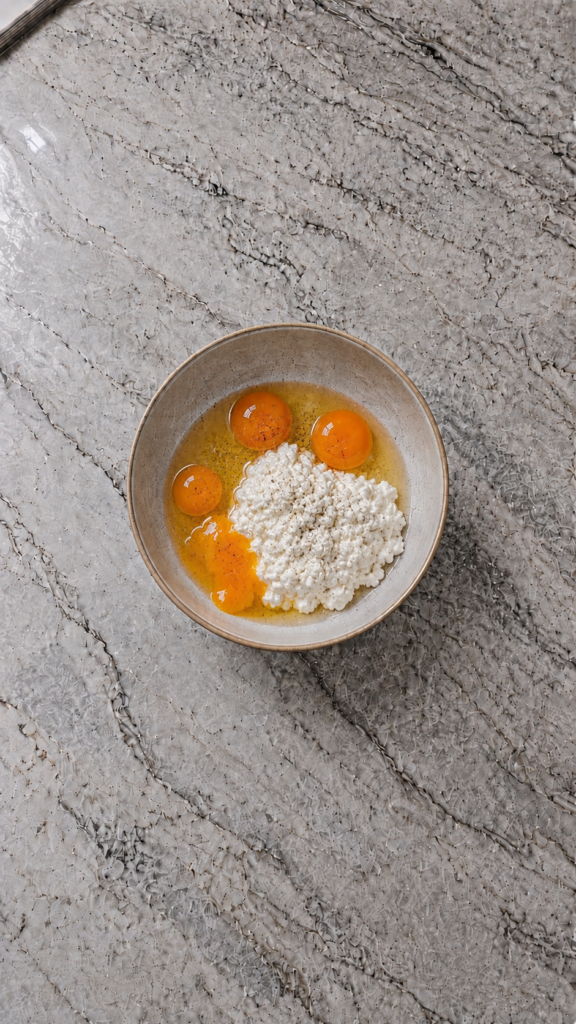 eggs cottage cheese and seasoning in bowl on marble countertop