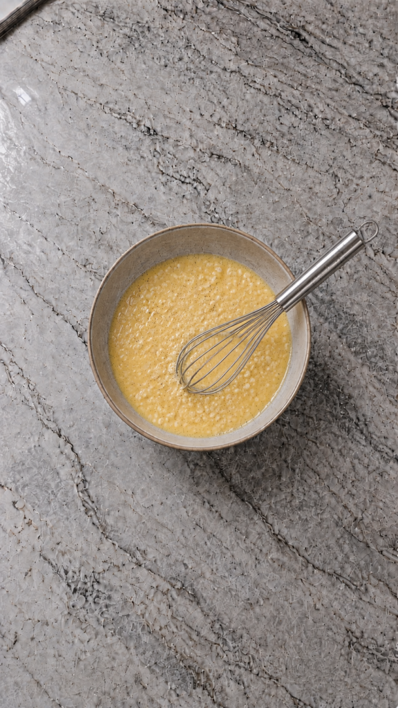 whisked egg and cottage cheese mixture in bowl with whisk on marble countertop
