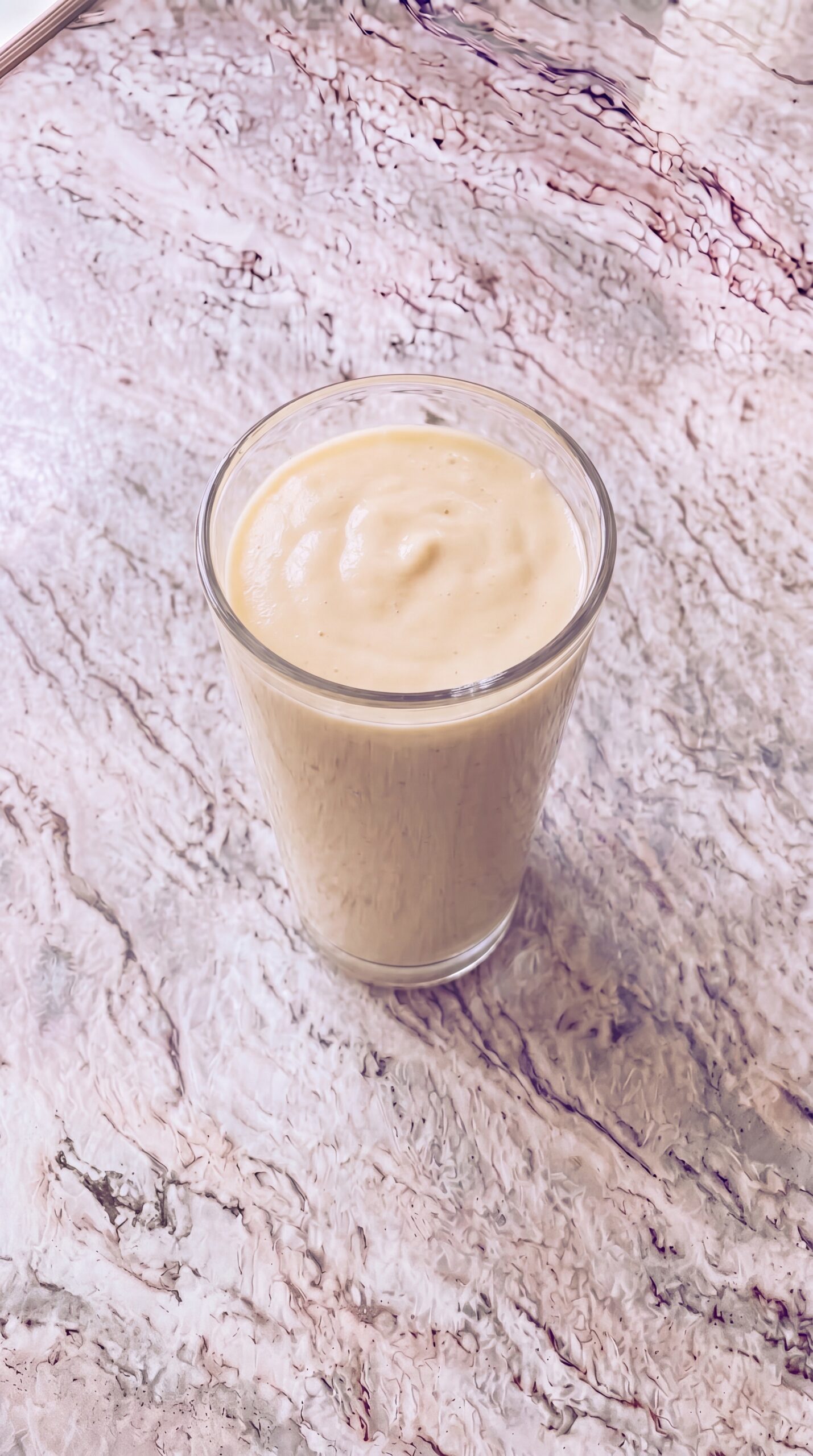 high protein breakfast smoothie in a tall glass on marble countertop